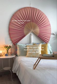 a bedroom with a pink fan on the wall above it's headboard and pillows