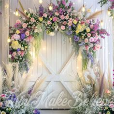 an arrangement of flowers and greenery is displayed in front of a white barn door