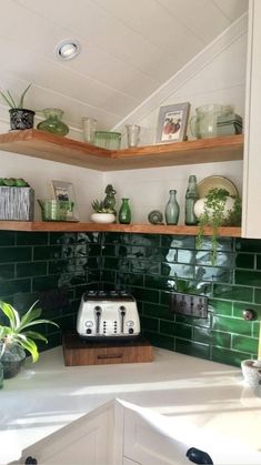 a kitchen with green tiles and wooden shelves