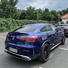 the rear end of a blue mercedes suv parked in a parking lot next to other cars