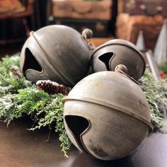 three gray pots sitting on top of a table next to pine cones and greenery