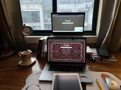 an open laptop computer sitting on top of a wooden desk next to a mouse and cell phone