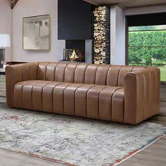 a brown leather couch sitting on top of a rug in a living room next to a fire place