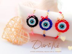 three beaded evil eye earrings sitting on top of a pillow next to a decorative object