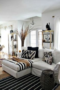 a living room with white couches and black and white rugs on the floor