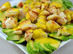 a white plate topped with shrimp and avocado covered in sauce on top of lettuce