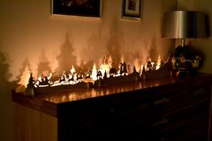 there are many candles on the table in front of the wall with pictures above it