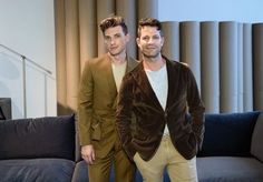 two men standing next to each other in front of a couch