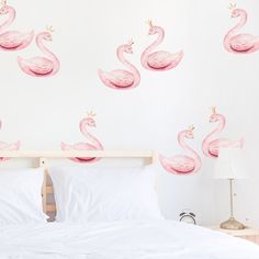 two pink flamingos sitting on top of a white bed