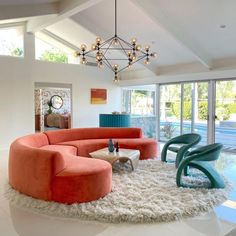 a living room filled with lots of furniture and a chandelier hanging from the ceiling