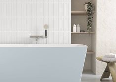 a white bath tub sitting in a bathroom next to a wooden shelf filled with towels