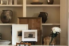 the shelves are filled with vases, pictures and other decorative items in white frames