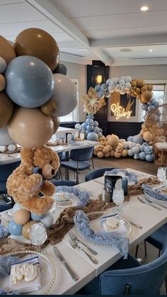 a teddy bear sitting on top of a table with balloons in the shape of animals