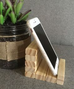 a cell phone sitting on top of a wooden block next to a potted plant