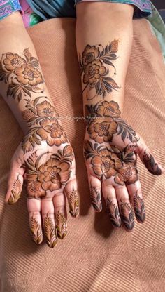 two hands with henna tattoos on them, one has flowers and the other has leaves