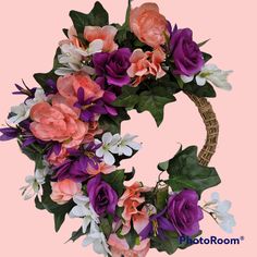 a floral wreath with pink, purple and white flowers on a light pink background is shown