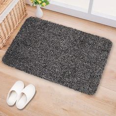 a pair of slippers sitting on the floor next to a door mat and basket