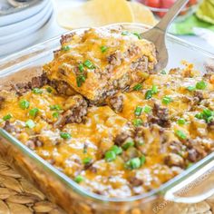 a casserole dish with meat, cheese and green onions in it is being lifted by a spatula