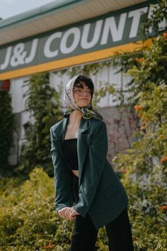 a woman standing in front of the j & j county sign wearing a green blazer and black pants