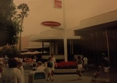 an old photo of people walking around in front of a building with a sign on it