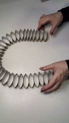 two hands are shown holding several pieces of paper in the shape of a spiral on a table