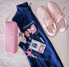 a pair of pink ballet shoes next to a blue satin bag and other items on a bed