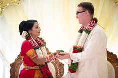 a man and woman standing next to each other in front of a white backdrop holding hands