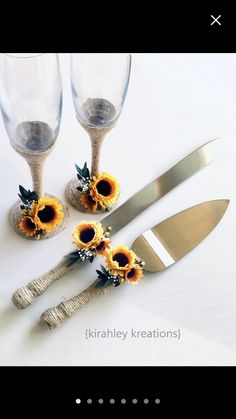 three sunflowers are sitting on the table next to two wine glasses and a knife