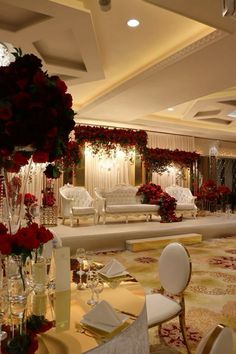 a room filled with lots of white furniture and red flowers in vases on top of tables