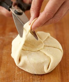 a person cutting dough with a pair of scissors