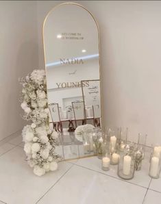 flowers and candles are arranged in front of a large mirror