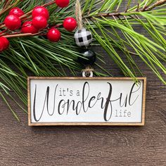 a wooden sign that says it's a wonderful life hanging from a pine tree