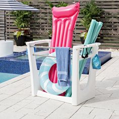 an inflatable beach chair next to a swimming pool with umbrellas and towels on it