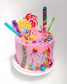 a pink birthday cake with candies, lollipops and candy on top