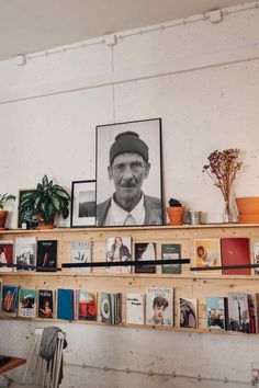 a shelf filled with books and pictures next to a potted plant on top of a wooden table