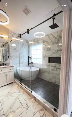 a bathroom with marble flooring and white walls, along with a glass enclosed shower stall