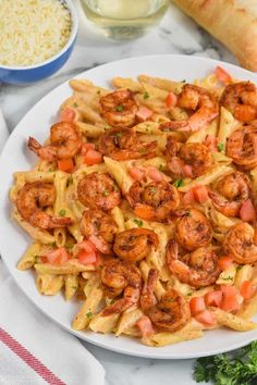 pasta with shrimp and tomato sauce on a white plate next to breadcrumbs