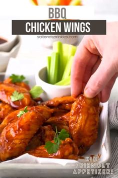 a person dipping sauce on chicken wings with celery and carrots in the background