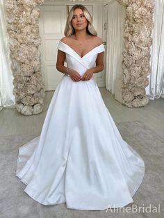 a woman wearing a white wedding dress standing in front of an archway with flowers on it