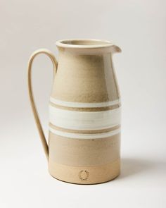 a white and tan striped pitcher on a white background with a circle logo in the center