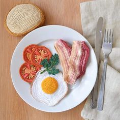 a white plate topped with an egg, bacon and tomato sandwich next to a fork