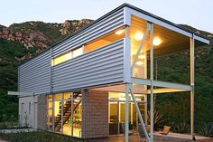 a modern house built into the side of a hill with stairs leading up to it