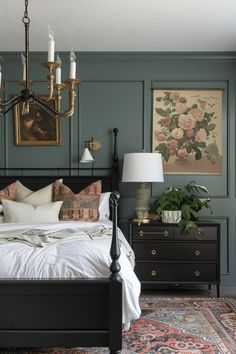 a bedroom with green walls and white bedding, chandelier above the bed