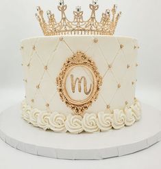 a white cake with gold decorations and a crown on top