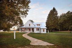 a white house sitting on top of a lush green field