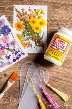 some flowers are sitting on the table next to paint and paper with crafting supplies