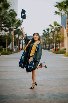 a woman in graduation gown and cap is throwing her hat into the air while smiling