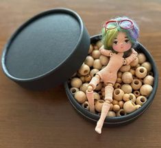 a small doll sitting in a bowl filled with wooden beads