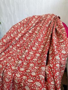 a bed covered with a red and white bedspread next to a pink pillow