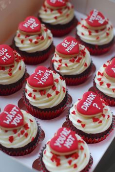 cupcakes with white frosting and red hearts are arranged in a box that says happy birthday